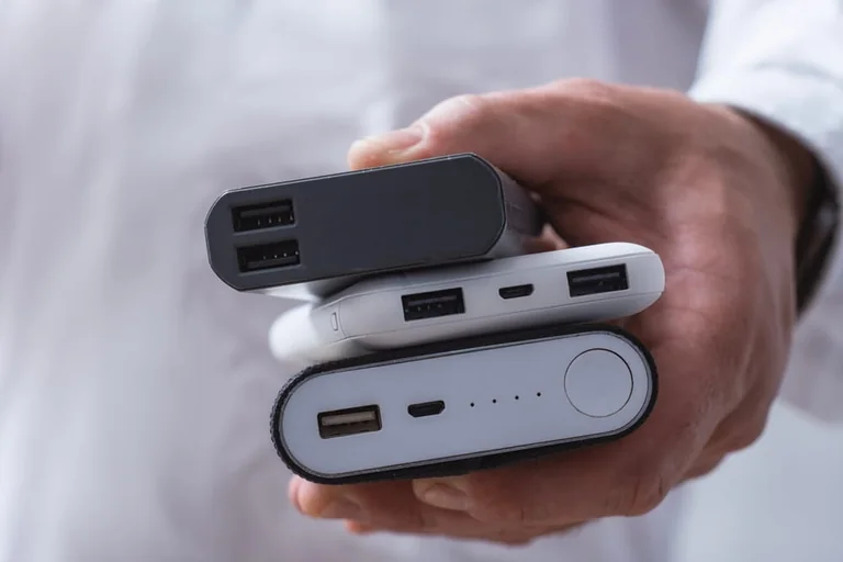 Drie powerbanks in een hand, met verschillende USB-aansluitingen.